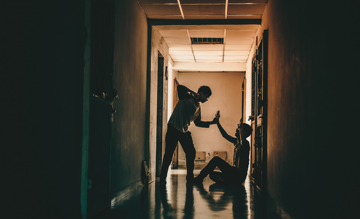 Silhouettes of two men fighting along a corridor