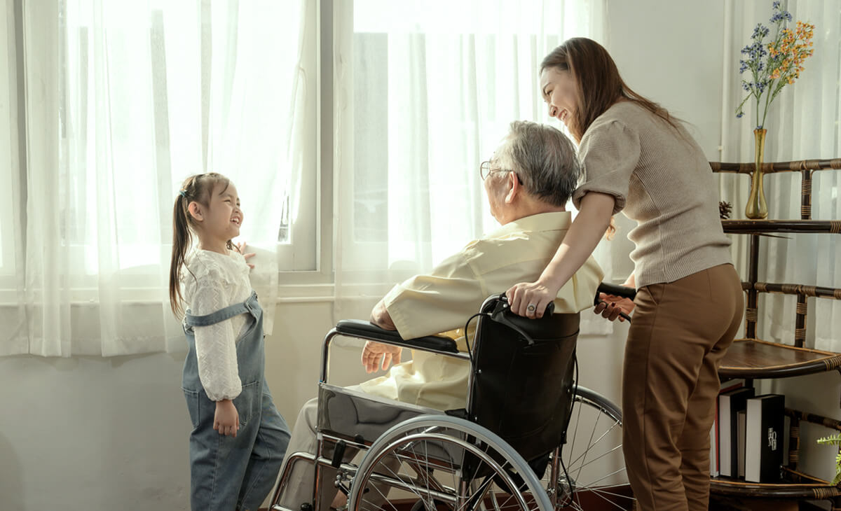 Elderly person in wheelchair sharing a moment with an adult and a child