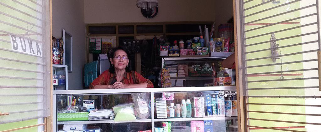 A woman stands behind a pharmacy counter, ready to assist customers with their medication needs.